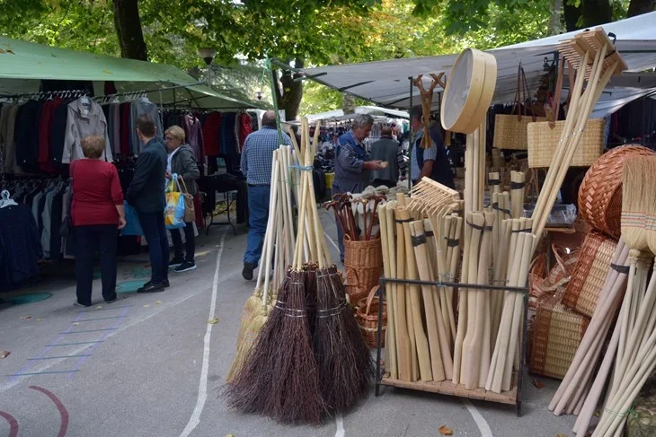 Outdoor market with brooms and handmade crafts.